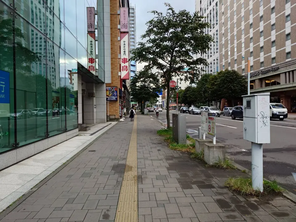 西4丁目通の歩道。前方にやきとり店の赤い看板が見える